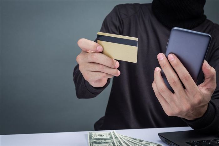 Мужчина держит смартфон и банковскую карту